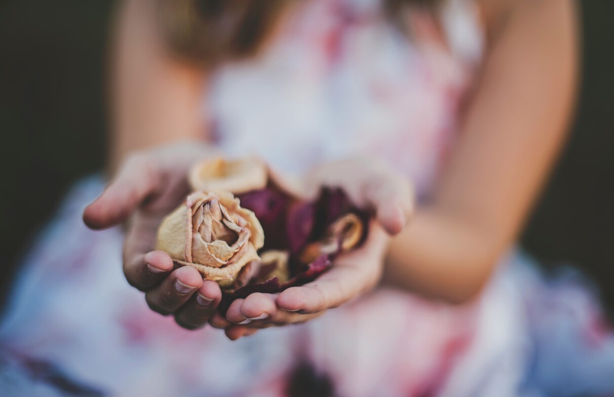 Woman holding dried roses symbolizing emotional longing and sensitivity