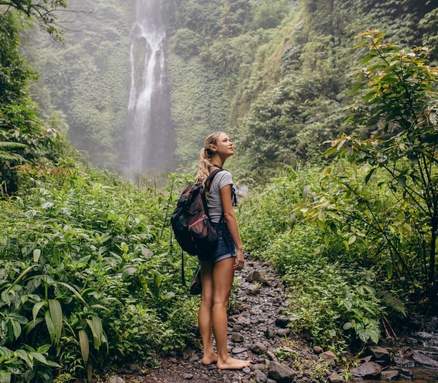 Woman walking through forest with backpack — symbolizing therapy for self-discovery and personal growth.