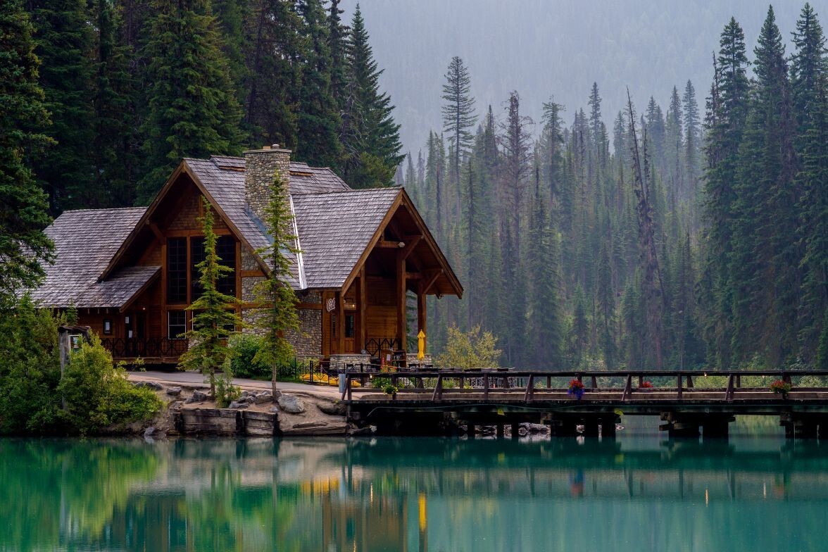 Serene cabin by the water and mountains representing reflection, peace, and the depth of healing through long-term therapy in Ontario.