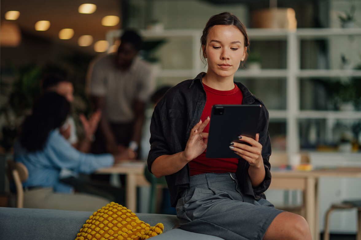 Woman in workplace setting feeling anxious while others network in the background