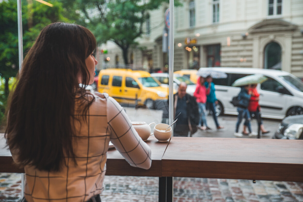 Woman sitting in cafe with big glass window and beautiful view of city street