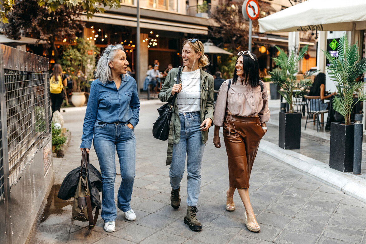 Three women walking together and talking, representing friendship, community, and social support.