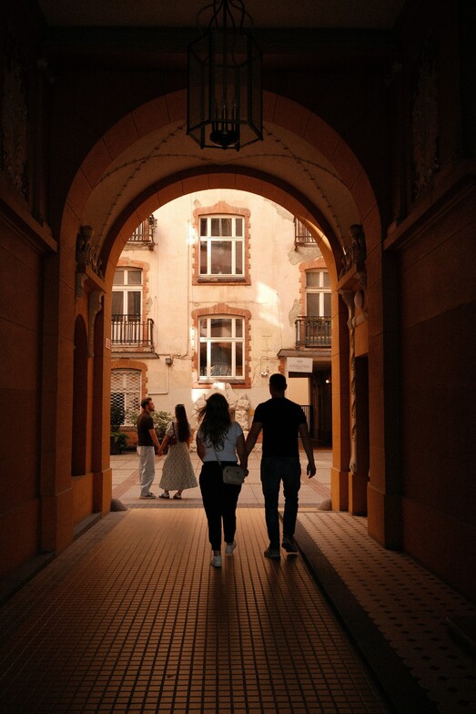 Couple holding hands and walking together through an arched passageway